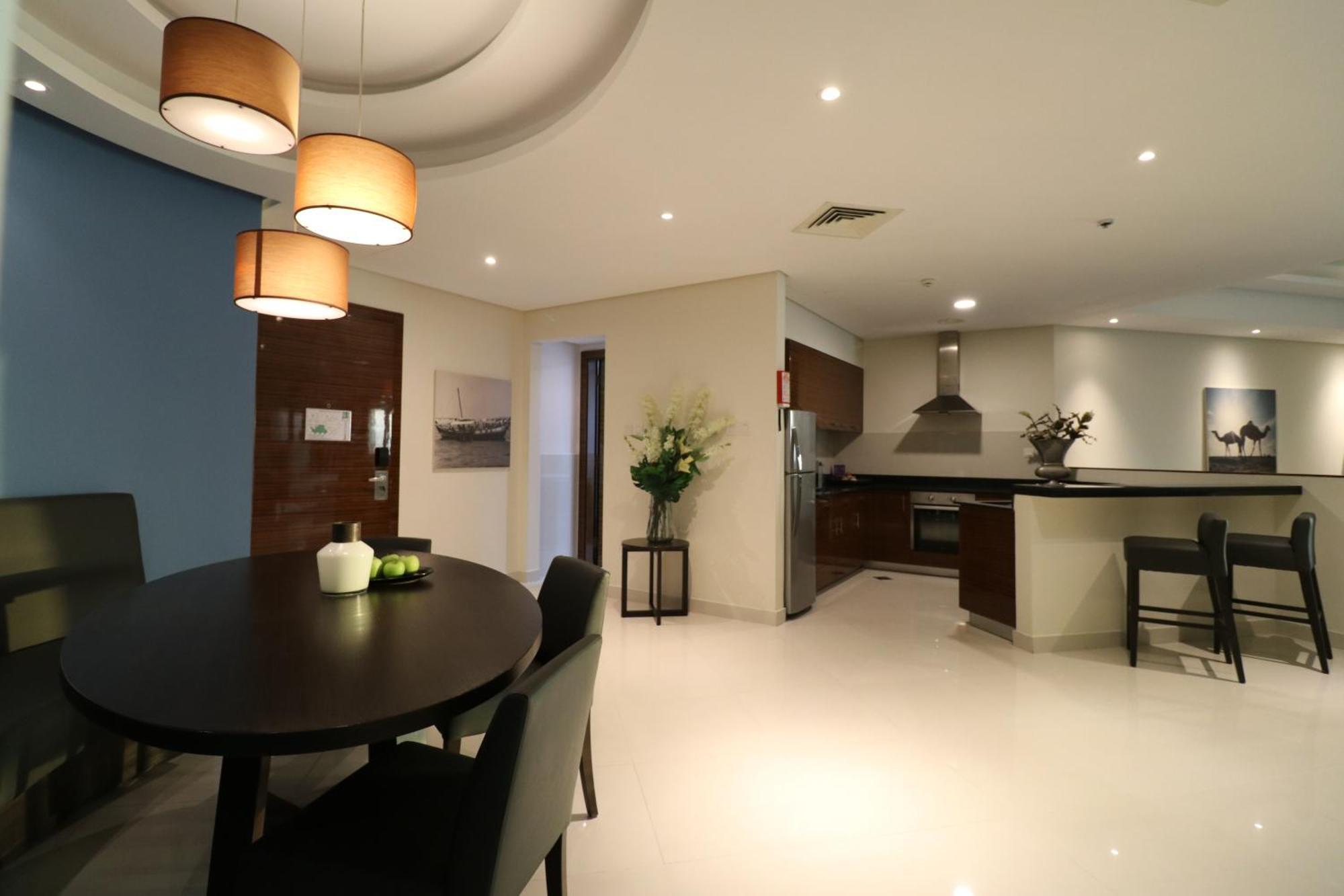Lagoona Beach Luxury Resort And Spa Manama Exterior foto The photo shows a modern, open-concept dining and kitchen area. On the left, there is a round dining table with black chairs, accompanied by a few decorative elements like a small vase and some fruit. The walls have a combination of light and dark to